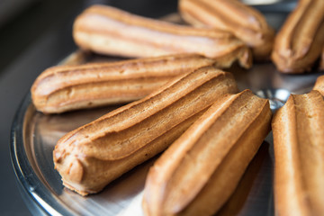 Fresh eclairs lying on a metal tray