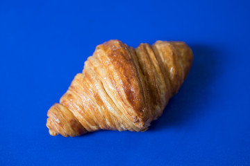 Freshly baked croissant lying on a blue board
