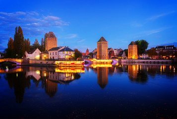 Fototapeta na wymiar medieval bridge Ponts Couverts of Strasbourg illuminated at night, France, toned