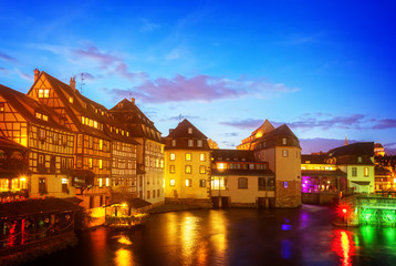 canal gateway and old houses of Petit France medieval district of Strasbourg illuminated at night, France , retro toned