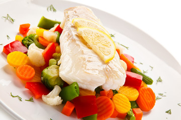 Fish dish - fried fish fillet and vegetables on white background