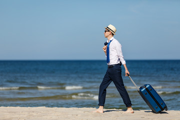 Businessman with suitcase relaxing on beach
