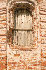 Window closed with wooden planks in the old abandoned brick building