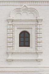 Fototapeta na wymiar Arched window with wooden frame in a white brick wall