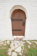 Arched wooden door in a white stone wall
