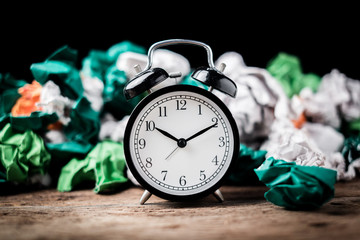 Alarm clock in a wastepaper concept for a time waste of time with cork board texture background