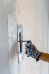 female worker hand and trowel plastering a white wall