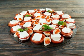 Plate full of delicious appetizers on the wooden table at the restaurant tomatoes cheese boiled eggs caviar eggplant vegetables food eating seafood mix menu gourmet concept.
