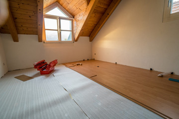 apartment room undergoing renovations with new wooden flooring and a red toolbox