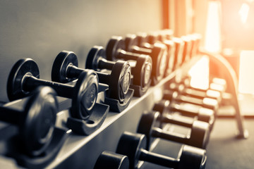 Healthy in the morning concept. Rows of dumbbells in the gym with high contrast and monochrome...