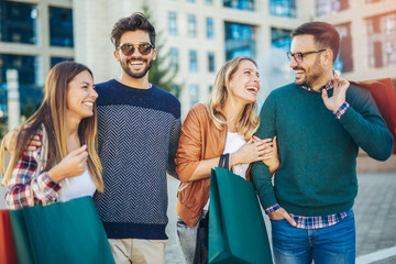 Group Of Friends Walking Along Street With Shopping Bags