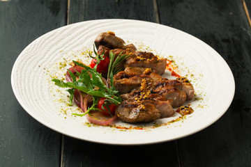 Grilled pork steak with spices, rosemary, arugula on a white plate