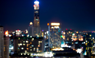 Naklejka premium Colorful of city modern buildings night abstract background, decorated with de-focus bokeh lights cities offices of reflecting building in Bangkok Thailand.