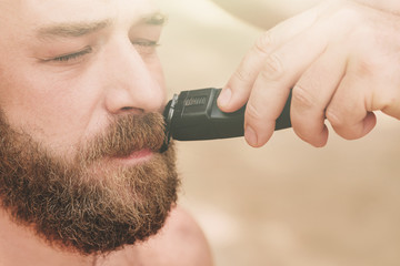 Haircut with a clipper of a bearded man