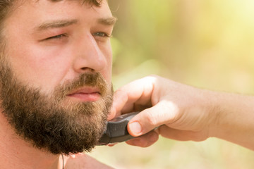 Handsome man at the time of haircut beard using hair clippers