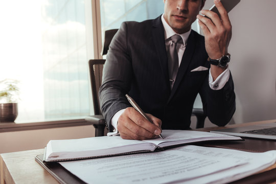 Businessman talking on mobile phone and making notes