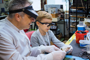 Fototapeta na wymiar IT teacher and small boy examining computer part.