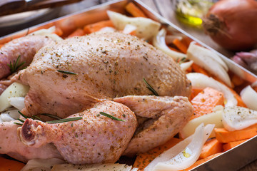 Whole Chicken Seasoned Uncooked Chopped Vegetables Carrots Yams Potatoes Onions in Baking Form Rosemary Olive Oil on Kitchen Table Preparation Process. Festive Christmas Easter New Year Dinner