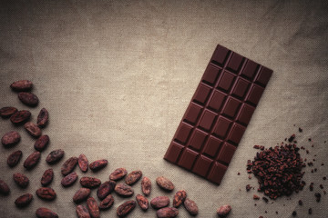 Dark chocolate and Raw cocoa beans. Background texture of old jute