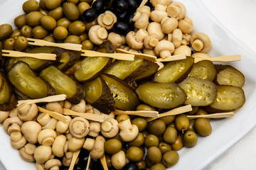 a plate of pickles on a buffet table. Selection of marinated mushrooms, salted cucumbers, olives, mustard in beans