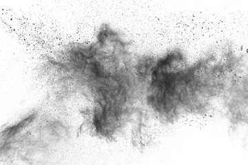 Black powder explosion against white background.The particles of charcoal splatted on white background. Closeup of black dust particles explode isolated on white background.