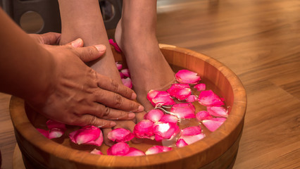 Obraz na płótnie Canvas Closeup photo of a female feet at spa salon on pedicure procedure. Female legs in water decoration the flowers.