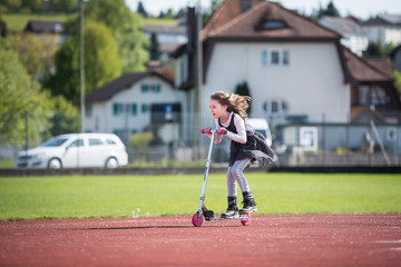 Little girl riding a scooter on a sports facility © cwzahner