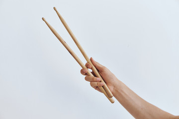 hand with drumsticks on a light background