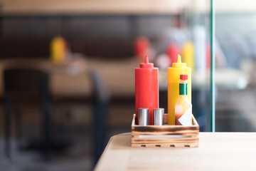 A cafe or restaurant tabletop setup with ketchup and mustared bottles and a salt and pepper shakers