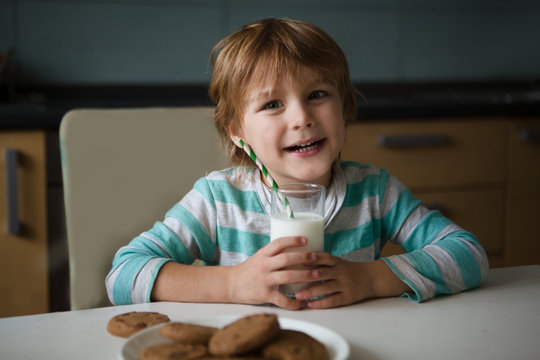 Three Little Boy Drink Milk And Eating Cookies In Kitchen. 