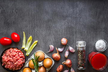 Composition of raw meat with vegetables and spice on wooden background