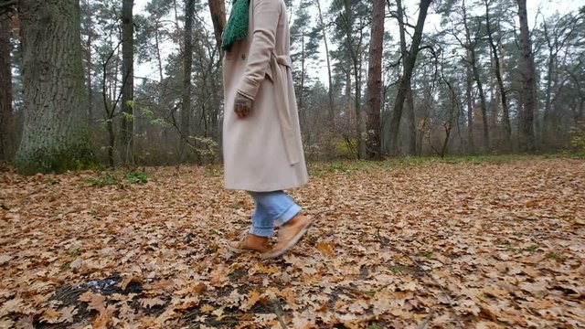 woman in a beige coat walking in an autumn park