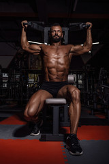 Fototapeta na wymiar Handsome man with big muscles working out in gym. Muscular bodybuilder doing exercises.