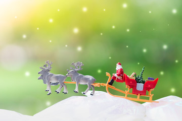 Miniature Santa Claus drive a wagon with a reindeer during the snowfall. Using as concept in Christmas day.