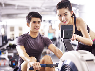 young asian couple working out using rowing machine