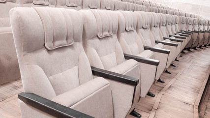 Interiors empty beige cinema chairs seats in low-key indoors.