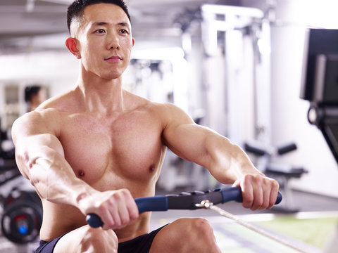 young asian man working out using rowing machine