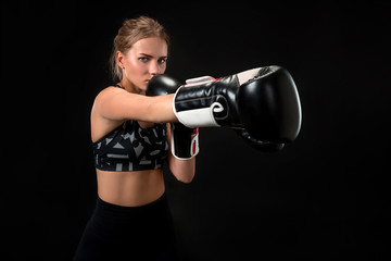 Beautiful female athlete in boxing gloves, in the studio on a black background. Focus on the glove