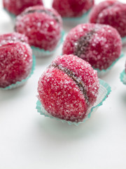 Dolcissime pesche all'alchermes ripiene di cioccolato e ricoperte di zucchero su sfondo bianco