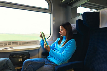 Woman traveling by train sitting near the window with tablet