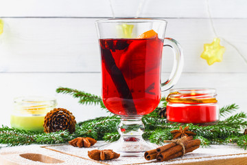 New Year's mulled wine in a glass on the background of twigs, candles and garlands.