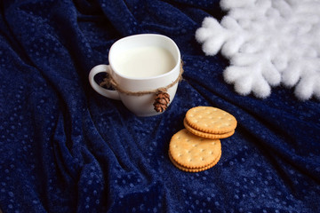 Milk in a white mug. Cracker.Against the background of velvet drapery.