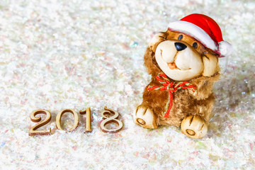 Wooden figures of 2018 on snow. Christmas atmosphere. The new year 2018. A toy dog is a symbol of the New Year.