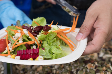 hand holding dish of fresh vegetable salad mix with Job's tears