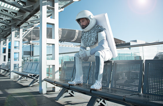 Spaceman wearing white uniform is sitting on bench and looking ahead with seriousness. Low angle. Copy space on right side