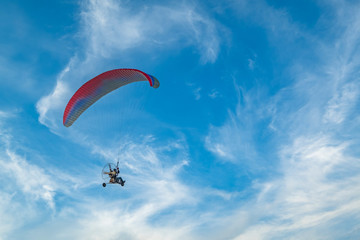 A flying paramotor on a vibrant sky with cloud. Extreme sport.