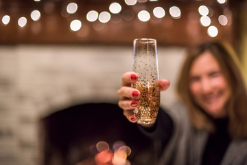 woman holding glass of champagne in front of fireplace