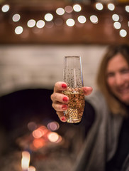 woman holding glass of champagne in front of fireplace
