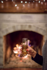 woman holding glass of champagne in front of fireplace