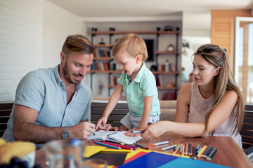 Fototapeta premium Mother and father drawing together with their child